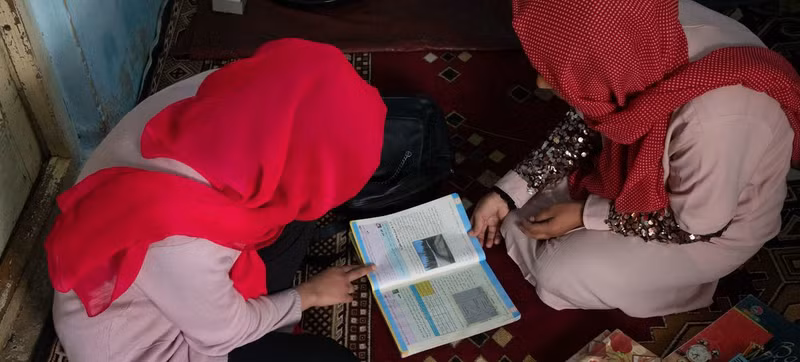 An Afghan girl studies at home with the help of her father after being denied the right to carry on studying at school. (Photo: UNICEF)