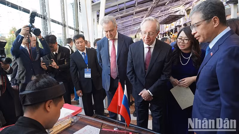 Ambassador Dang Minh Khoi, Russian Deputy Foreign Minister Mikhail Galuzin, and Chairman of the Committee for External Relations of St. Petersburg Evgeny Grigoriev watch calligraphy at the ceremony marking 78th anniversary of Vietnam's National Day in Russia. (Photo: XUAN HUNG)