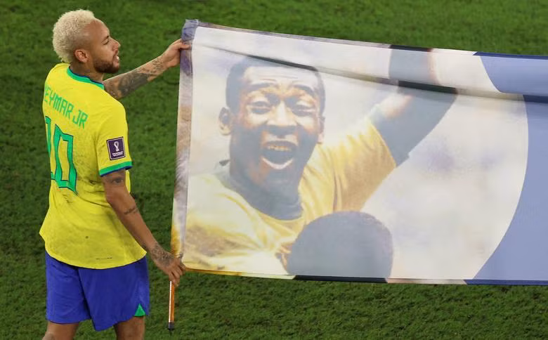 Brazil's Neymar carries a banner of former Brazil player Pele after the match. REUTERS/Pedro Nunes