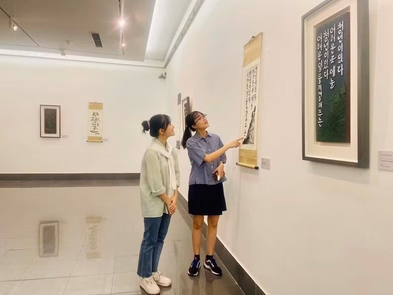 Young people admire the calligraphy works featuring quotes from President Ho Chi Minh on display at the exhibition.