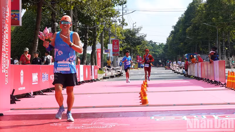 An athlete carries a bouquet of lotus during the run to promote the image of Dong Thap – the land of lotuses. An athlete carries a bouquet of lotus during the run to promote the image of Dong Thap – the land of lotuses.
