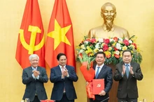 Prime Minister Pham Minh Chinh (second from left) and National Assembly Chairman Tran Thanh Man (far right) present the appointment decision and offer flowers to Nguyen Hong Dien. (Photo: VNA)