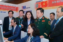 General Nguyen Trong Nghia (standing, front, second from right) visits Viet Nam News Agency reporters covering the 14th National Party Congress on January 20. (Photo: VNA)