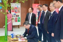 Professor Dr Le Van Loi, President of the Viet Nam Academy of Social Sciences, writes New Year wishes at the display area featuring the ‘cay neu’ (neu pole) – a traditional Vietnamese symbol representing hopes for a peaceful and auspicious year ahead.