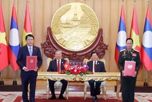 Vietnamese Party General Secretary To Lam (second, left), and Party General Secretary and President of Laos Thongloun Sisoulith witness the exchange of memorandum of understanding (MoU) on cooperation between the Vietnamese Ministry of Public Security and the Lao Ministry of National Defence on building a Viet Nam - Laos friendship road. (Photo: VNA)
