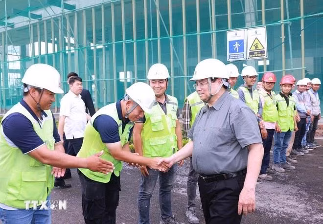 Prime Minister Pham Minh Chinh (R) encourages workers and engineers at the Viet Nam Exhibition Fair Centre project site. (Photo: VNA)