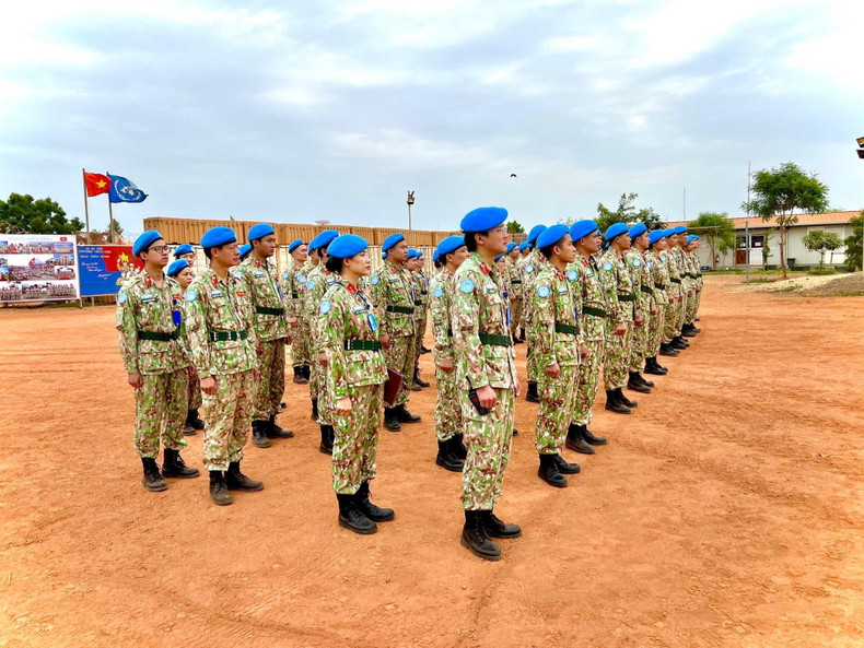 In a solemn atmosphere, all officers and staff sing out load the National Anthem under the red flag with a yellow star of Vietnam that is fluttering beside the flag of the United Nations.
