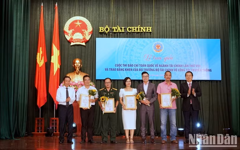 Deputy Minister of Finance Nguyen Duc Chi presents the first prizes to the winning reporters. (Photo: Trung Hung)
