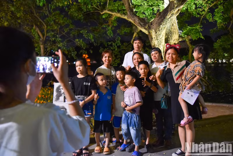 Members of a family pose for a photo by Hoan Kiem Lake.