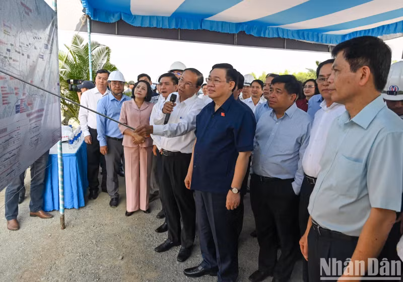 Chairman Vuong Dinh Hue listens to a report on the project's construction progress.