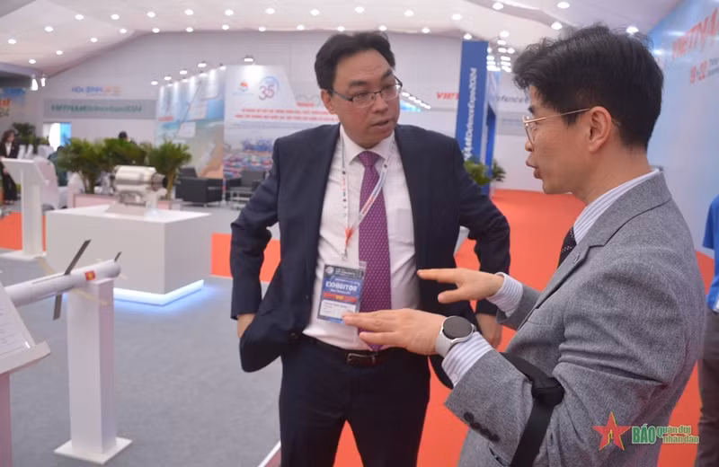 Chairman of the Board of Directors of MK Aerospace (left) talks with visitors to the company’s booth. 