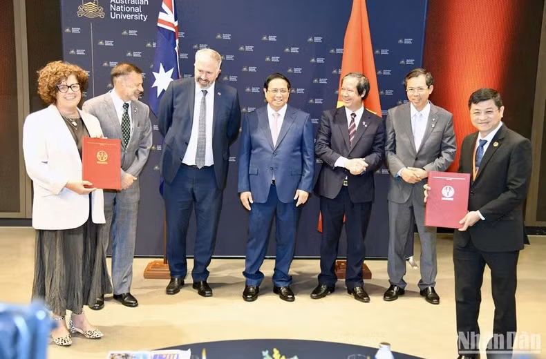 Prime Minister Pham Minh Chinh (fourth, left) witnesses the exchange of cooperation documents between Vietnamese and Australian universities. (Photo: VNA) 