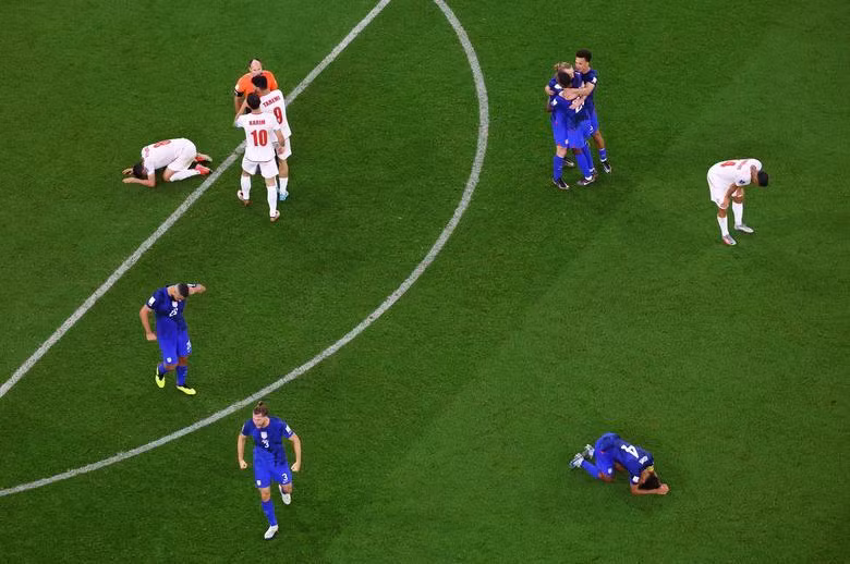 United States players celebrate qualifying for the knockout stages as Iran players look dejected after being eliminated from the World Cup. (Photo: REUTERS)