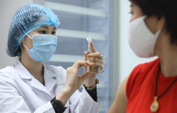 A health worker prepares to administer COVID-19 vaccine to a woman. (Photo: VNA)