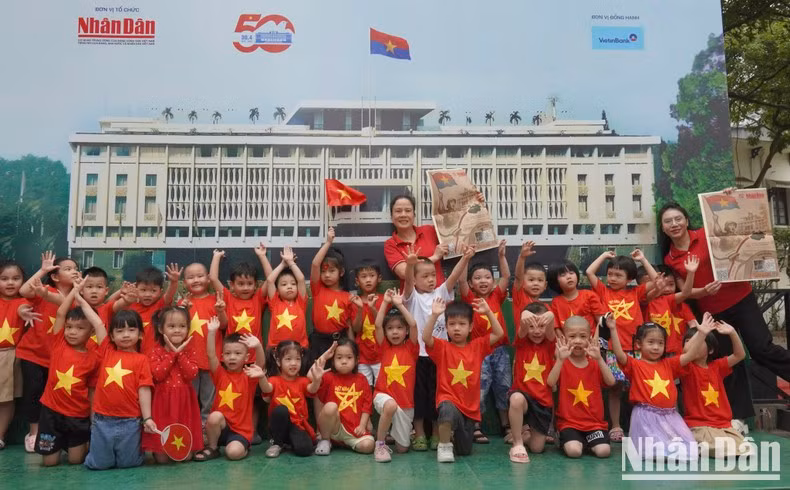 Children from Thang Tam (August) Kindergarten, dressed in red T-shirts with yellow stars, excitedly pose for a photo during their visit to the exhibition.