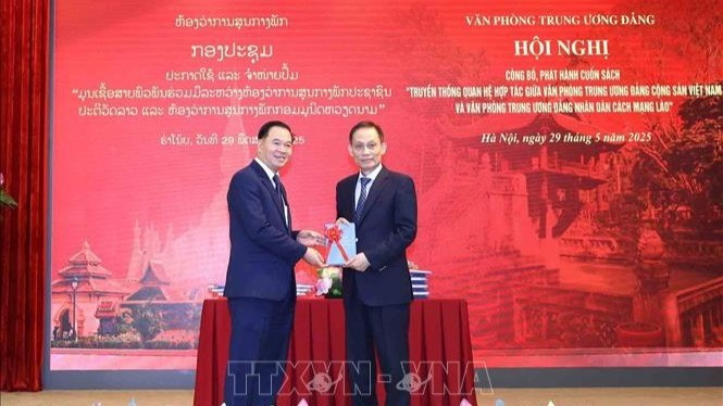 Le Hoai Trung, Secretary of the CPV Central Committee and Chief of the CPV Central Office, presents a book to Thongsalith Mangnomek, Secretary of the LPRP Central Committee and Chief of the LPRP Central Office. (Photo: VNA)