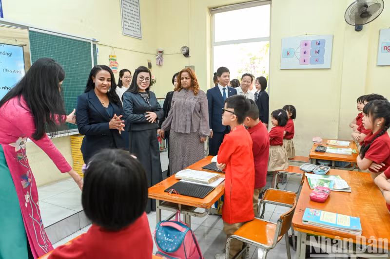 The two ladies visit a classroom and interact warmly with the students.