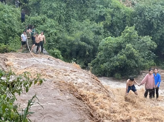The rescue team use a rope to rescue the children trapped in the middle of the stream when the floodwaters appear (Photo: baogialai.com.vn) 