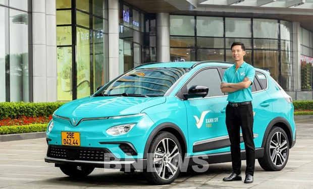 A car and driver of the electric taxi service. (Photo: VNA)