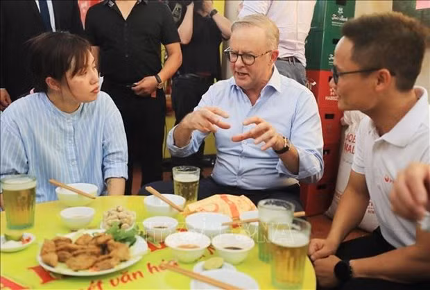 Australian Prime Minister Anthony Albanese talks about Vietnamese dishes at the lunch with young people. (Photo: VNA)