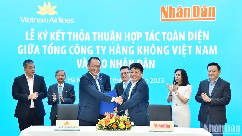 Deputy Editor-in-Chief of Nhan Dan Newspaper Que Dinh Nguyen and Member of the Board of Management and General Director of Vietnam Airlines Le Hong Ha exchange the cooperation agreement in the presence of leaders of the two agencies.