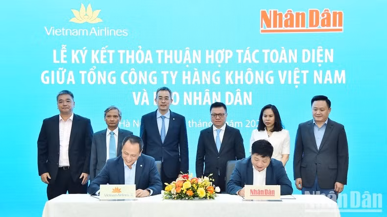 Leaders from Nhan Dan Newspaper and Vietnam Airlines witness the signing of the comprehensive cooperation agreement.