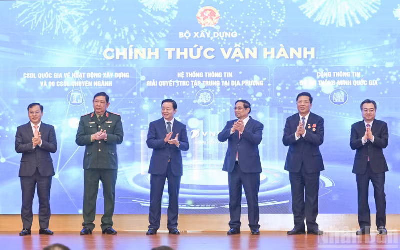 Prime Minister Pham Minh Chinh (third from right) and officials launch the Ministry of Construction’s new information technology systems at the conference on December 21. (Photo: NDO)