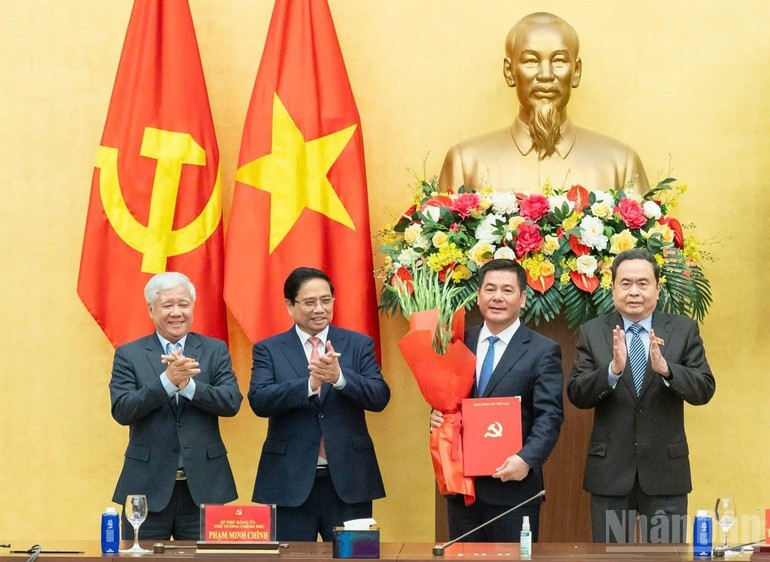 Prime Minister Pham Minh Chinh (second from left) and National Assembly Chairman Tran Thanh Man (far right) present the appointment decision and offer flowers to Nguyen Hong Dien. (Photo: VNA)