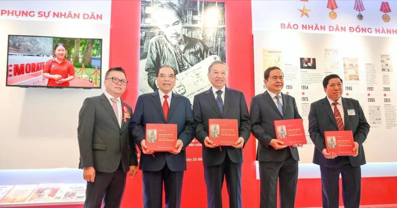 General Secretary To Lam and other Party and State incumbent and former leaders receive the book titled “Uncle Ho’s articles on Culture and Journalism by in Nhan Dan Newspaper” at the Nhan Dan exhibition’s pavilion. 