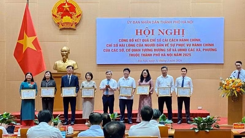 Vu Dai Thang, Chairman of the Ha Noi Municipal People’s Committee, presents certificates of merit to units with high rankings in administrative reform in 2025.