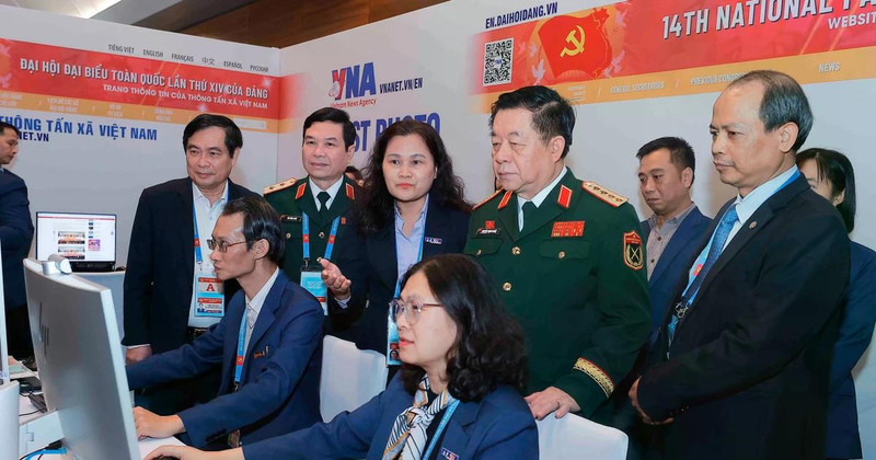 General Nguyen Trong Nghia (standing, front, second from right) visits Viet Nam News Agency reporters covering the 14th National Party Congress on January 20. (Photo: VNA)