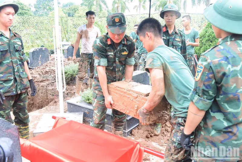 Officers and soldiers transport unidentified martyrs’ remains at Mai Dich Cemetery in Phu Dien Ward to the sampling area. (Photo: HUU THU)