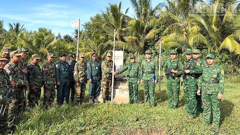 Officers and soldiers from both sides pose for a photo at a border marker during the joint patrol.