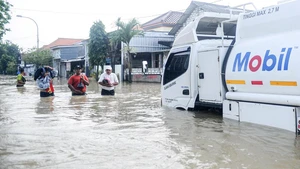 People wade through flood water after heavy rain in Benjeng village of Gresik Regency, East Java, Indonesia, June 10, 2025. ( Photo: Xinhua)