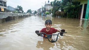 A boy pushes his bike through floodwaters in South Tangerang, Banten Province, Indonesia, Jan. 23, 2026. (Photo: Xinhua)