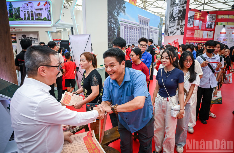 The joy of a small family as they queue to receive the special Nhan Dan supplement. (Photo: Thanh Dat)