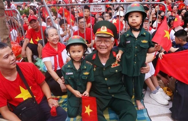 A war veteran and his grandchildren are waiting to watch the rehearsal at the Hung Vuong - Tran Phu intersection. (Photo: VNA) A war veteran and his grandchildren are waiting to watch the rehearsal at the Hung Vuong - Tran Phu intersection. (Photo: VNA)