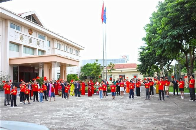 Cán bộ, nhân viên Đại sứ quán Việt Nam tại Lào giơ cao lá cờ đỏ sao vàng hướng về Tổ quốc. (Ảnh: Xuân Tú/PV TTXVN tại Lào) lao1-250825.jpg