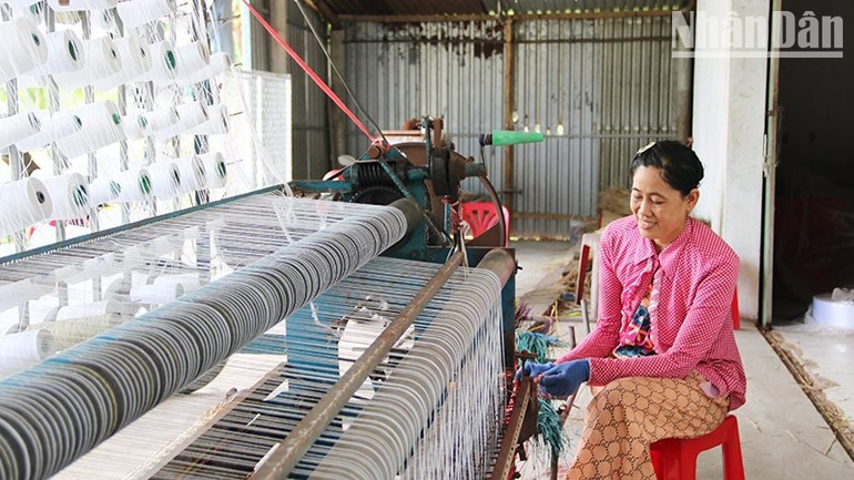 Nguyen Thi Minh Trang, owner of a mat weaving workshop in Duc My Hamlet, Nhi Long Commune, weaving mats with a semi-automatic weaving machine. ndo-tr-a2.jpg