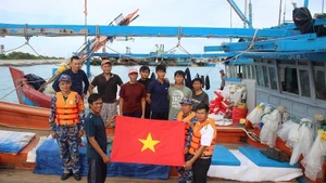 Officers and soldiers on Song Tu Tay Island present gifts and food to fishermen as they take shelter from storms.