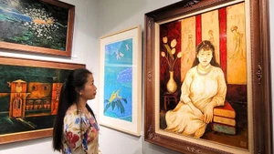 A visitor admires paintings at the exhibition.