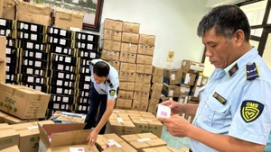 Ha Noi market surveillance officers inspect a business establishment suspected of violations. (Photo: Luu Quyen)