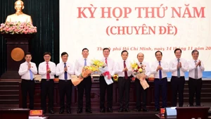 Ho Chi Minh City Party Secretary Tran Luu Quang presents flowers to the new vice chairs of the municipal People’s Committee.