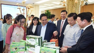 Prime Minister Pham Minh Chinh visits a booth displaying OCOP products. (Photo: Tran Hai)