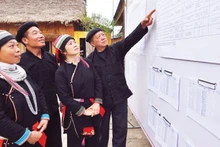 Voters review the list of candidates publicly posted at the cultural house of Nam Dam Hamlet, Quan Ba Commune (Tuyen Quang Province) (Photo: VNA)