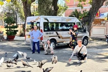 Visitors at Thang Tam communal house call doves to the courtyard.
