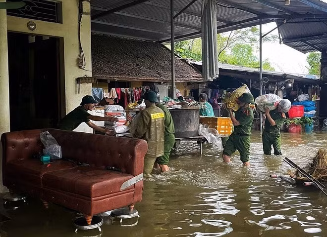 Police and security forces help people move their assets in a flooded area. (Photo: VNA)