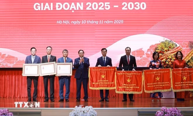Prime Minister Pham Minh Chinh presents the First and Third Class Labour Orders and the Government's emulation flag to collectives and individuals with outstanding achievements in the patriotic emulation movement at the event. (Photo: VNA)