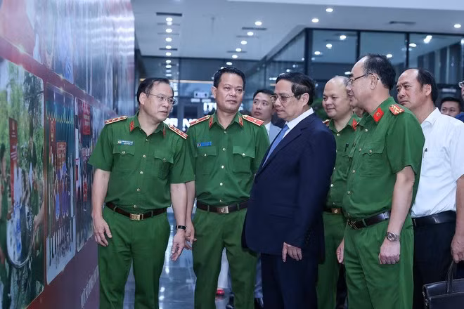 PM Pham Minh Chinh and public security officials look at photos on martyrs' DNA testing activities. (Photo: VNA)