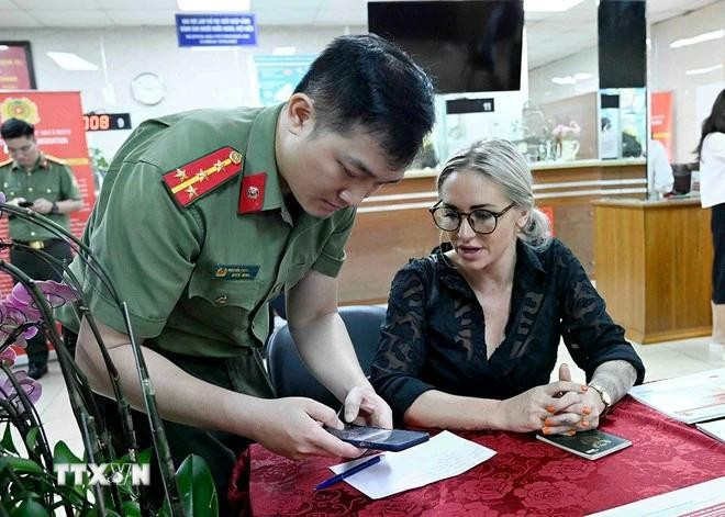 A police officer instructs a foreigner how to register for a level-2 electronic identification account. (Photo: VNA)